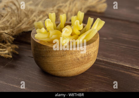 Menge ganze rohe Nudeln Gemelli in Houten mit Jute-stoff auf braunem Holz Stockfoto