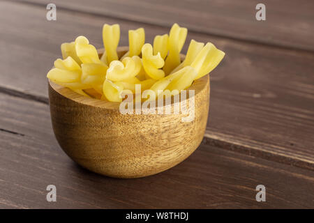 Menge ganze rohe Nudeln Gemelli in Houten auf braunem Holz Stockfoto