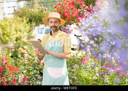 Reife bärtige Gärtner in Arbeitskleidung auf der Suche nach on-line-Informationen Stockfoto