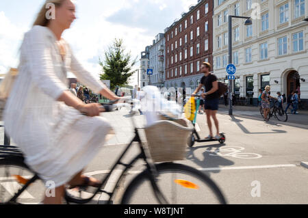 Kopenhagen Bike - eine Frau, ein Fahrrad und ein Mann auf einem Roller in das Stadtzentrum von Kopenhagen, Kopenhagen, Dänemark Europa Stockfoto