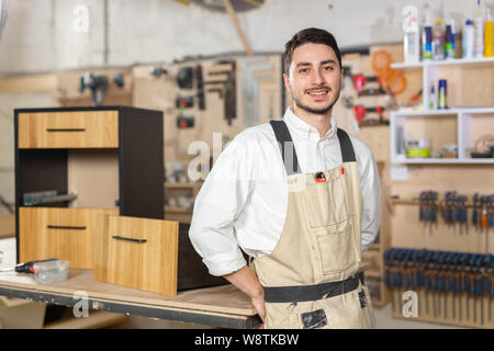 Möbelfabrik, kleines Unternehmen und Personen Konzept - Porträt eines lächelnden männlichen Arbeitnehmer bei der Herstellung Stockfoto