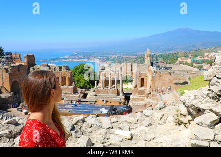 Schöne junge weibliche model in den Ruinen des antiken griechischen Theaters in Taormina mit dem Vulkan Etna und das Ionische Meer im Hintergrund, Sizilien, Ita Stockfoto