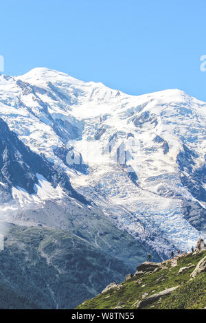 Wanderer oben auf einem Felsen mit Blick auf die erstaunliche Mont Blanc in den Alpen, in der Nähe von Chamonix, Frankreich. Höchster Gipfel der Französischen Alpen und Europa. Sommer Saison. Abenteuer, Wandern Konzept. Touristische Orte. Stockfoto