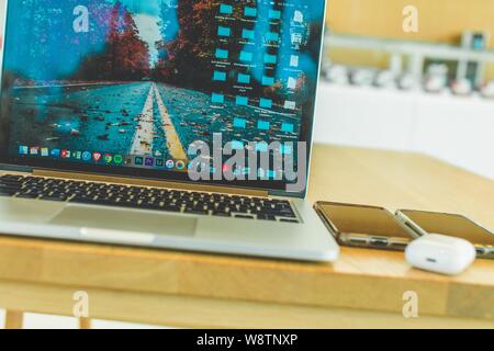 Nahaufnahme eines grauen Laptops in der Nähe von zwei Smartphones Und airpods Stockfoto