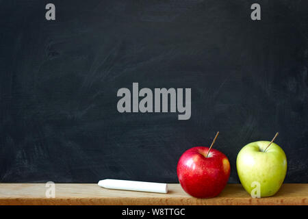 Zurück Konzept zur Schule, closeup schwarzer Kreide in Chalk Flecken chalk Board und zwei Äpfel Rot und Grün, selektiver Fokus, Copyspace Stockfoto