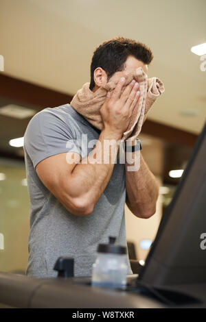 Taille bis Portrait von stattlicher Mann v auf Laufband im Fitnessstudio und Abwischen Gesicht mit Handtuch, Kopie Raum Stockfoto