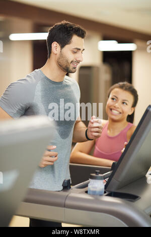 Portrait von gutaussehenden jungen Mann laufen auf Laufband im Fitnessstudio und glücklich lächelnd genießen Workout Stockfoto