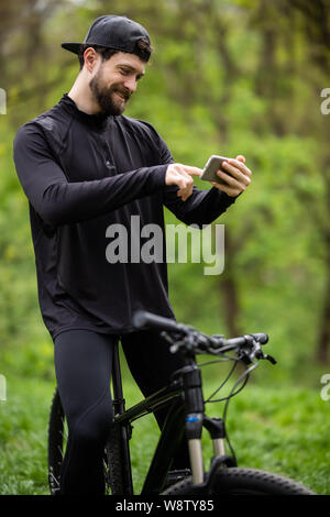 Happy bärtiger Mann Radfahrer Fahrten im sonnigen Wald auf einem Mountainbike. Stockfoto