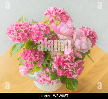 Hortensien und Rosen in einer verzierten Kanne. Stockfoto