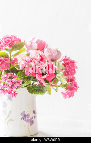 Hortensien und Rosen in einer verzierten Kanne. Stockfoto