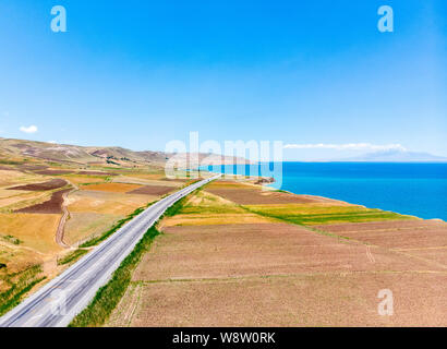 Luftaufnahme des Vansees, in der Türkei. Felder und Klippen mit Blick auf das kristallklare Wasser der größte See der Türkei. Straßen entlang der See Stockfoto