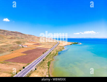 Luftaufnahme des Vansees, in der Türkei. Felder und Klippen mit Blick auf das kristallklare Wasser der größte See der Türkei. Straßen entlang der See Stockfoto