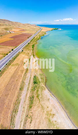 Luftaufnahme des Vansees, in der Türkei. Felder und Klippen mit Blick auf das kristallklare Wasser der größte See der Türkei. Straßen entlang der See Stockfoto