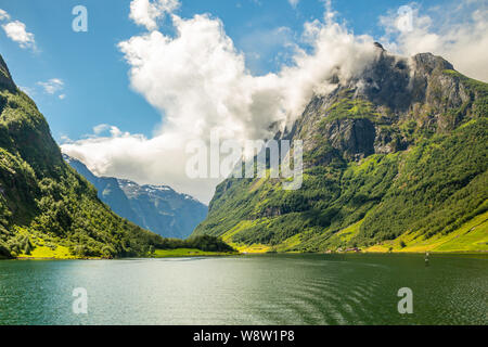 Green mountain Peak oberhalb des kleinen Dorfes in Naeroy Fjord, Aurlan, Sogn og Fjordane County, Norwegen Stockfoto