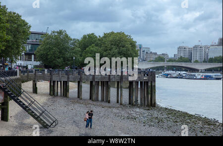 Paar gesehen zu Fuß am Sandstrand der Themse an der South Bank in London während der Ebbe an einem Nachmittag im August. Stockfoto