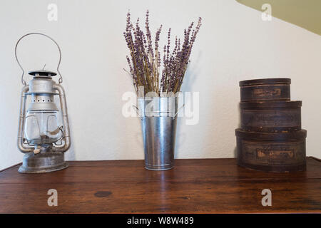 Top antiker Kiefernholz Kommode mit alten Öl lampe gestaltet aus verzinktem Metall Vase und Vintage runde Seifenkisten im Schlafzimmer Stockfoto