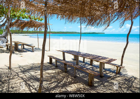 Helle malerischen Blick auf Holz- Picknick Tischen unter rustikale Brasilianischen Palapas auf einer einsamen Strand in Bahia, Brasilien Stockfoto