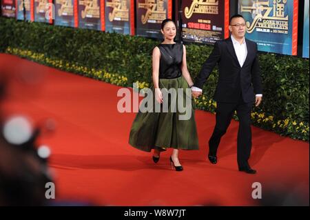 Der chinesische Regisseur und Schauspieler Jiang Wen, rechts, hält die Hände mit seinem Schauspielerin Frau Zhou Yun, als sie auf dem roten Teppich für die Premiere ihres neuen m Stockfoto