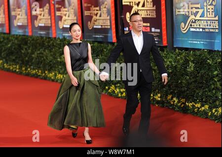 Der chinesische Regisseur und Schauspieler Jiang Wen, rechts, hält die Hände mit seinem Schauspielerin Frau Zhou Yun, als sie auf dem roten Teppich für die Premiere ihres neuen m Stockfoto