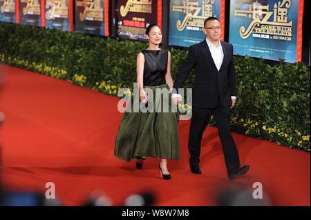 Der chinesische Regisseur und Schauspieler Jiang Wen, rechts, hält die Hände mit seinem Schauspielerin Frau Zhou Yun, als sie auf dem roten Teppich für die Premiere ihres neuen m Stockfoto