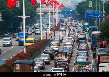 Massen von Fahrzeugen bewegen sich langsam in einem Stau an einer Straße mit chinesischen nationalen Flaggen dekorierte der Nationale Tag Urlaub in Shenzhen City zu feiern. Stockfoto