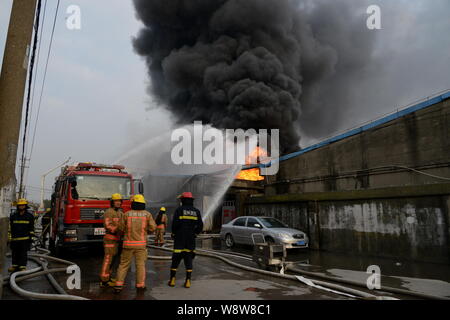 Chinesische Feuerwehrmänner Schlauch Wasser das Feuer durch Explosionen in der chemischen Warehouses verursacht zu löschen, verletzt drei Menschen, an der Wenzhou chemischen Markt Stockfoto