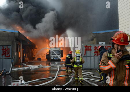 Chinesische Feuerwehrmänner Schlauch Wasser das Feuer durch Explosionen in der chemischen Warehouses verursacht zu löschen, verletzt drei Menschen, an der Wenzhou chemischen Markt Stockfoto