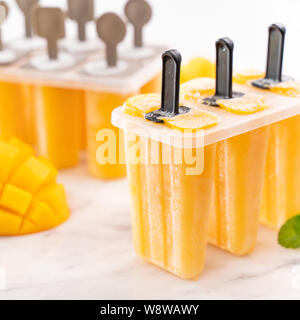Frische mango Obst popsicle Eis in die plastische Gestaltung der Box auf hellem Marmor tisch. Sommer Stimmung Konzept Produkt Design, bis zu schließen. Stockfoto