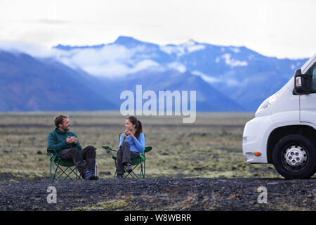 Reisen Paar durch mobile Motor home RV Wohnmobil. Die Menschen in den Stühlen entspannen Camping und Reisen auf Island im Wohnmobil sitzen. Junges Paar Kaffeegenuss in der Natur Landschaft. Stockfoto