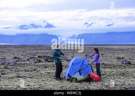 Camping paar Pitching Zelt nach dem Wandern. Freunde, Zelt für die Nacht nach der Wanderung mit Zahnrad und Rucksäcke. Aktiver Lebensstil Bild mit kaukasischen Mann und die asiatische Frau. Stockfoto