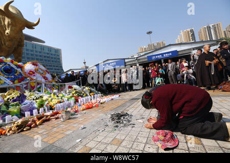 Trauernde kniet nieder und Bogen für die Opfer der gewalttätigen Terroranschlag vor der Goldenen Bulle statue am Bahnhof in Kunming trauern Stockfoto