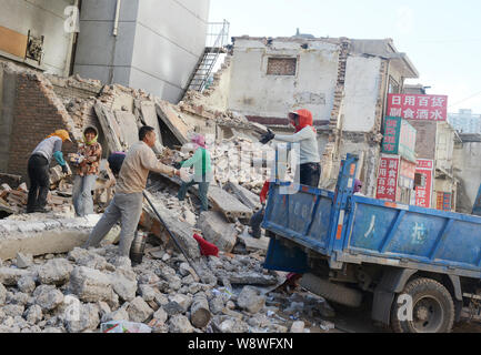 ------ Chinesische Wanderarbeiter pass auf Ziegelsteine auf die Trümmer der alten Häuser für die Neugestaltung in einem Elendsviertel in Changchun Stadt demoliert, North China Stockfoto