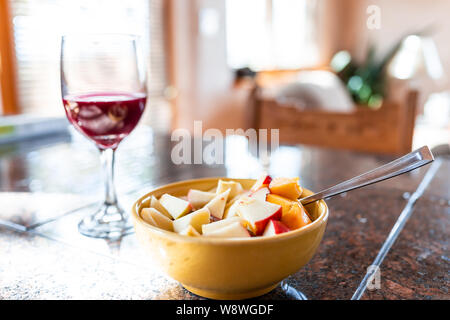 Nahaufnahme von einer Schüssel mit Apfel und Pfirsich Slices auf Porridge mit bokeh Hintergrund Rotwein Glas auf der Arbeitsplatte in der Küche oder im Restaurant Stockfoto