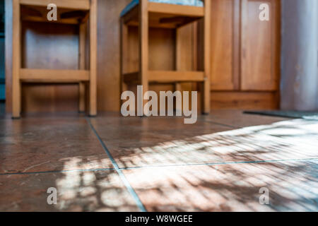 Moderne Küche Zimmer fliesenboden niedrigen Winkel closeup mit Insel und hölzernen Barhockern am Zähler in Haus oder Wohnung mit Sonnenlicht aus dem Fenster Stockfoto