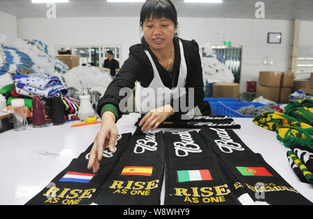 Ein weiblicher chinesischer Arbeiter untersucht fan Schals der Niederlande, Spanien, Italien und Portugal für die Brasilien WM 2014 zu einem produziert f Stockfoto