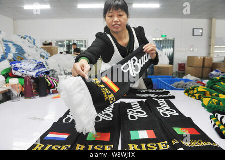 Ein weiblicher chinesischer Arbeiter untersucht fan Schals aus Spanien, den Niederlanden, Italien und Portugal für die Brasilien WM 2014 zu einem produziert f Stockfoto