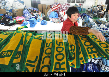 Ein weiblicher chinesischer Arbeiter untersucht fan Schals von Brasilien und Socceroos (Australien National Association Football team) für die Brasilien Welt 2014 hergestellt Stockfoto