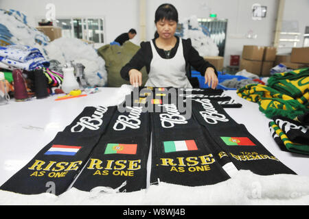 Ein weiblicher chinesischer Arbeiter untersucht fan Schals aus Spanien, den Niederlanden, Italien und Portugal für die Brasilien WM 2014 zu einem produziert f Stockfoto