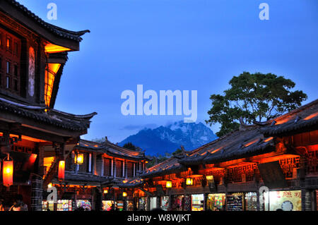 Nacht Blick auf alte Gebäude gegen die Jade Dragon Snow Mountain (Yulong Snow Mountain) in der Altstadt von Lijiang, Lijiang, Southwest China Yunn Stockfoto