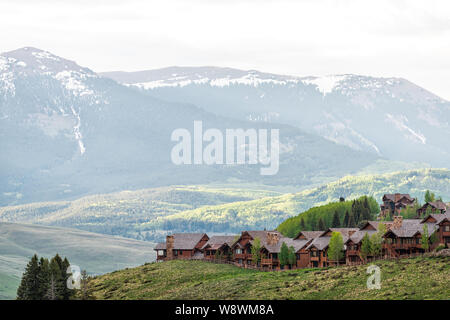 Mount Crested Butte Dorf in Colorado im Sommer mit sunrise von hölzernen Unterbringung Häuser auf den Hügeln mit grünen Bäumen, Stockfoto