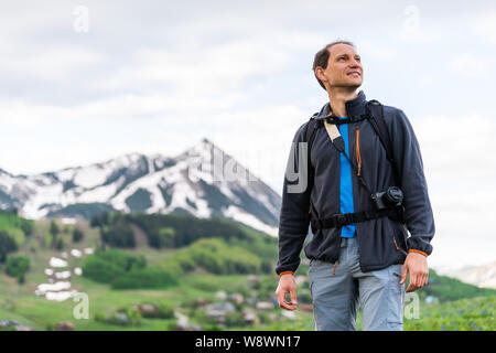 Mann glücklich Wandern suchen, um sich über Snodgrass Trail mit bokeh Hintergrund Blick auf Mount Crested Butte, Colorado Peak und Dorf im Sommer Stockfoto