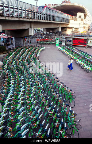 Ein Fußgänger geht letzten Zeilen der Fahrräder zum Mieten an einer Vermietstation in Peking, China, 14. Juni 2014. Peking wird weitere 15.000 Fahrräder hinzufügen für Stockfoto