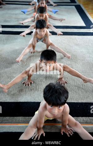 Junge chinesische Jungs verbiegen ihre Körper mit ihren Händen auf dem Boden zu halten Gymnastik an einer Gymnastik Training Center in Bozhou ci zu üben Stockfoto