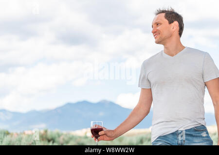 Mann mit roten Wein aus der Sicht von Taos Sangre de Cristo Mountains von Sabrosa Tal bokeh Hintergrund im Hinterhof Stockfoto