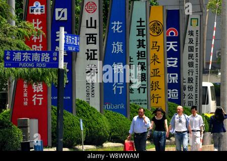 ---- Fußgänger vorbei an Schildern von chinesischen und ausländischen Unternehmen in der Lujiazui Finanzviertel in Pudong, Shanghai, China, 12. Stockfoto