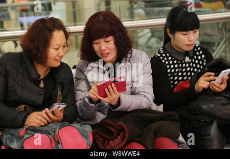 ------ Chinesische Frauen verwenden ihr Smartphone im Internet surfen bei einem Einkaufszentrum in Stadt Xuchang, Zentrale China Provinz Henan, am 22. Februar 2014. Stockfoto