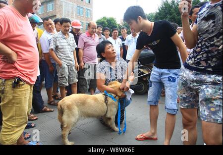 Ein Tier recht Aktivist kniet sich und bittet ein junger Mann ihr einen Hund auf einem Markt in Vorbereitung für den Hund Fleisch Festival in Yulin Stadt zu verkaufen, Stockfoto