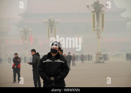 Ein chinesischer Polizeioffizier das Tragen einer Maske Patrouillen Vergangenheit Touristen auf dem Platz des Himmlischen Friedens im heavy Smog in Peking, China, 26. Februar 2014. Ein Resi Stockfoto