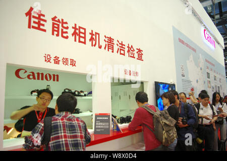 ------ Chinesische Mitarbeiter die Besucher am Stand von Canon im 17. China International Foto & Imaging Maschinen und Techn Stockfoto