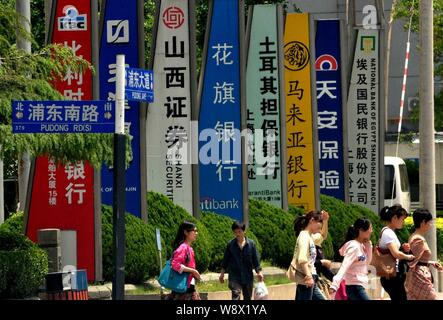 ---- Fußgänger vorbei an Schildern von chinesischen und ausländischen Unternehmen in der Lujiazui Finanzviertel in Pudong, Shanghai, China, 12. Stockfoto